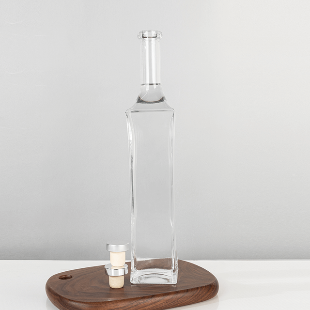 Szklana butelka na alkohol o pojemności 700 ml, o wydłużonym kształcie i eleganckich zaokrągleniach