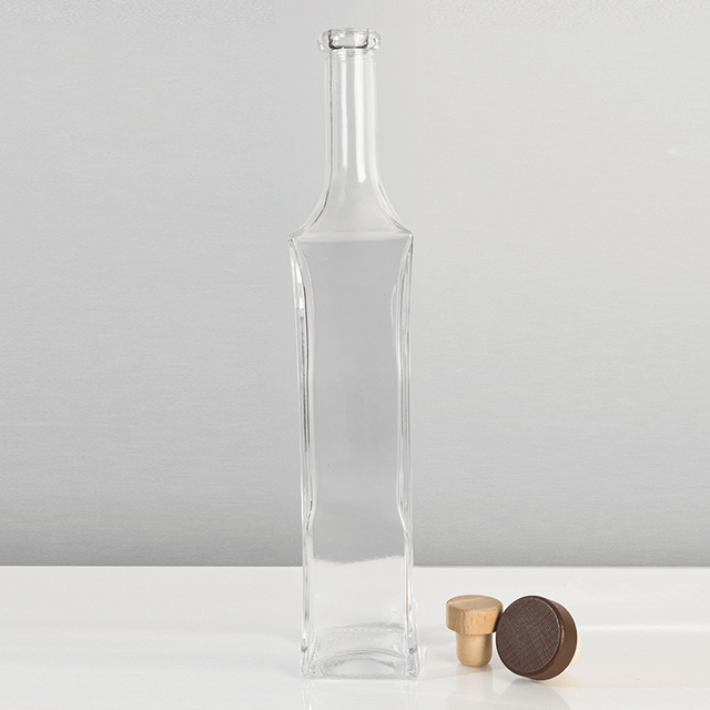 Szklana butelka na alkohol o pojemności 700 ml, o wydłużonym kształcie i eleganckich zaokrągleniach