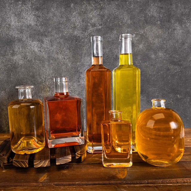 W zaopatrzonych przezroczystych kwadratowych okrągłych szklanych butelkach na alkohol
